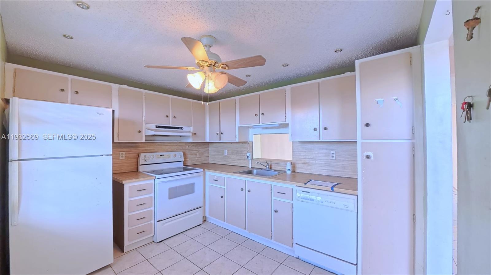 A kitchen features white appliances, light-colored cabinets, a ceiling fan, and tiled flooring — 111 SE 3rd Ave # 502, Dania Beach FL 33004, DANIA BEACH, FL