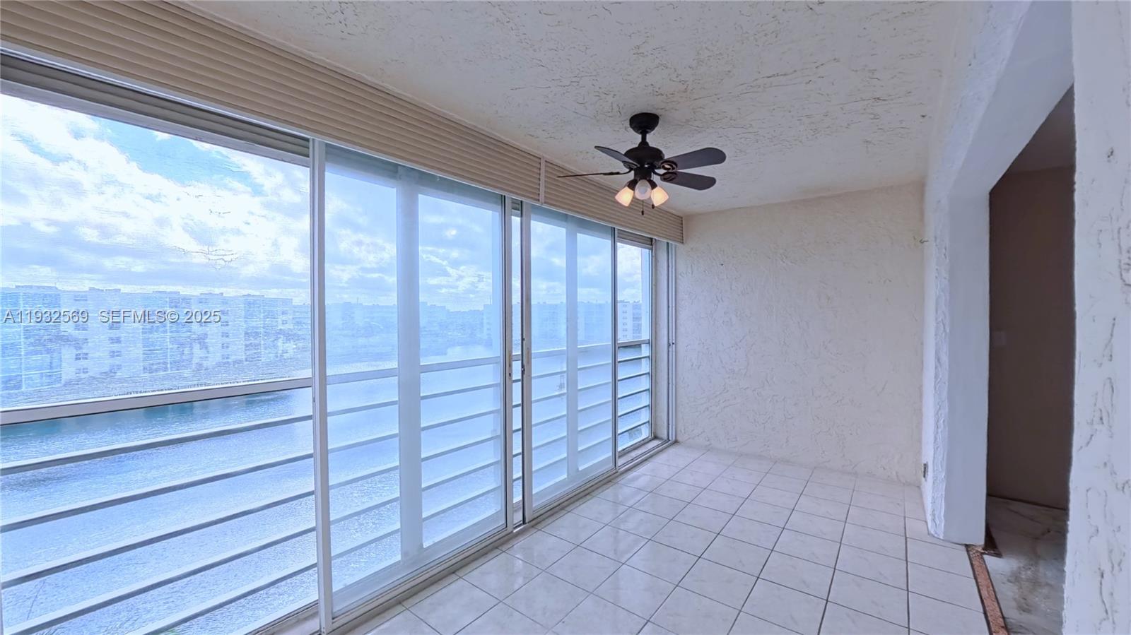A sunroom with white tile floors, a ceiling fan, and large sliding glass doors overlooking water — 111 SE 3rd Ave # 502, Dania Beach FL 33004, DANIA BEACH, FL