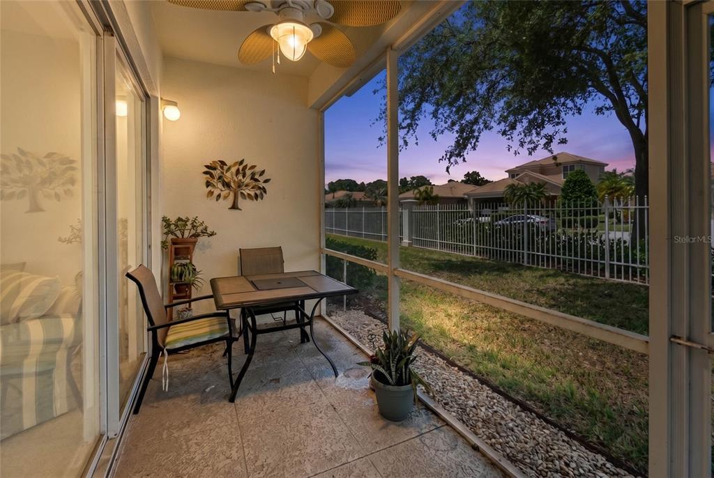 A screened-in patio features a small dining set, a ceiling fan, and a fenced yard — 7343 FOUNTAIN PALM CIRCLE UNIT na, BRADENTON, FL