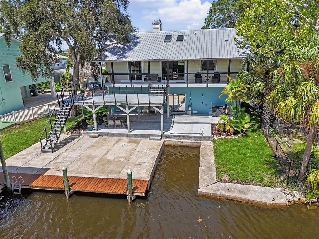 An elevated waterfront house features a metal roof, a large deck, and a private boat slip — 12390 W STANDISH, HOMOSASSA, FL