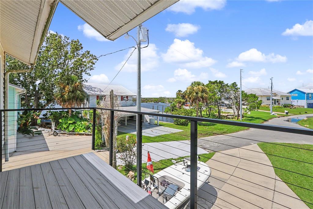 An elevated deck with a black metal railing overlooks a boat, driveway, and waterfront canal — 12390 W STANDISH, HOMOSASSA, FL