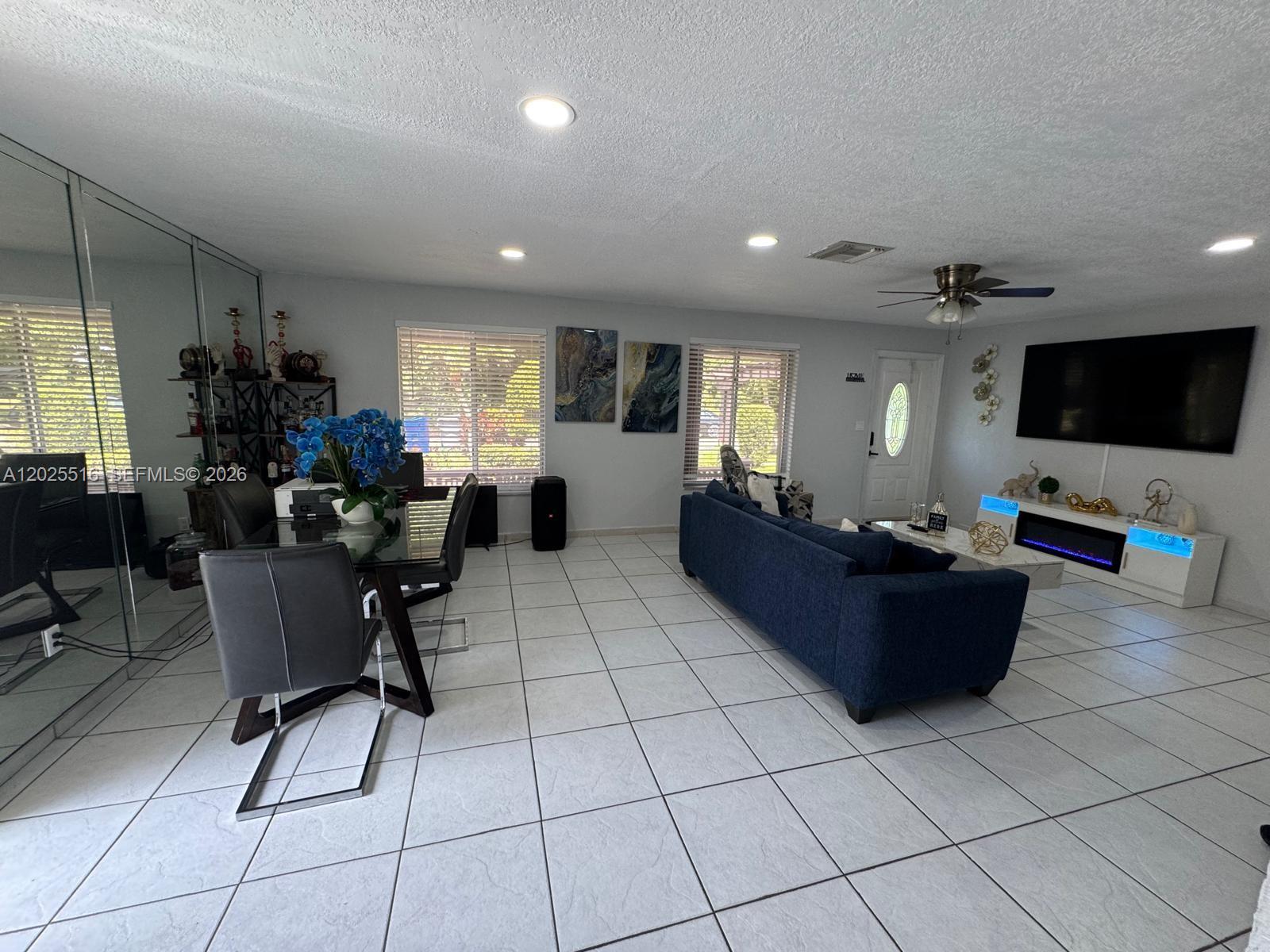 A living and dining area features white tile floors, a blue sofa, and mirrored walls — 5844-5846 Pierce St, Hollywood FL 33021, HOLLYWOOD, FL