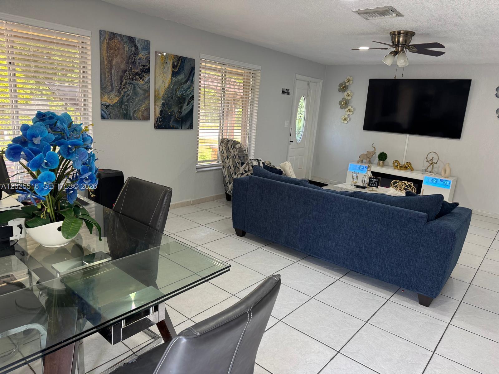 A living room and dining area with tile floors, a blue sofa, and a glass table — 5844-5846 Pierce St, Hollywood FL 33021, HOLLYWOOD, FL