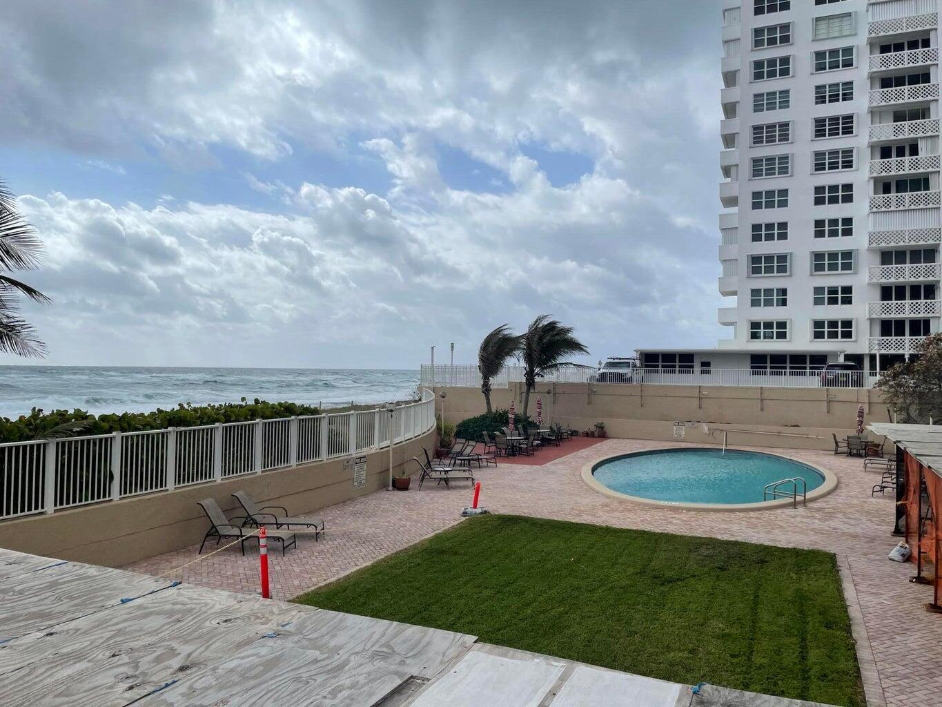 An outdoor pool area with a lawn, lounge chairs, and a view of the ocean — 1180 S Ocean Boulevard # 5c, Boca Raton FL 33432, BOCA RATON, FL