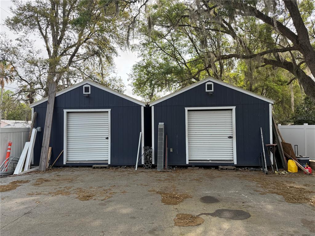 Two dark blue storage sheds with white roll-up doors stand side-by-side on a paved lot — 9478 W MARQUETTE LANE, CRYSTAL RIVER, FL
