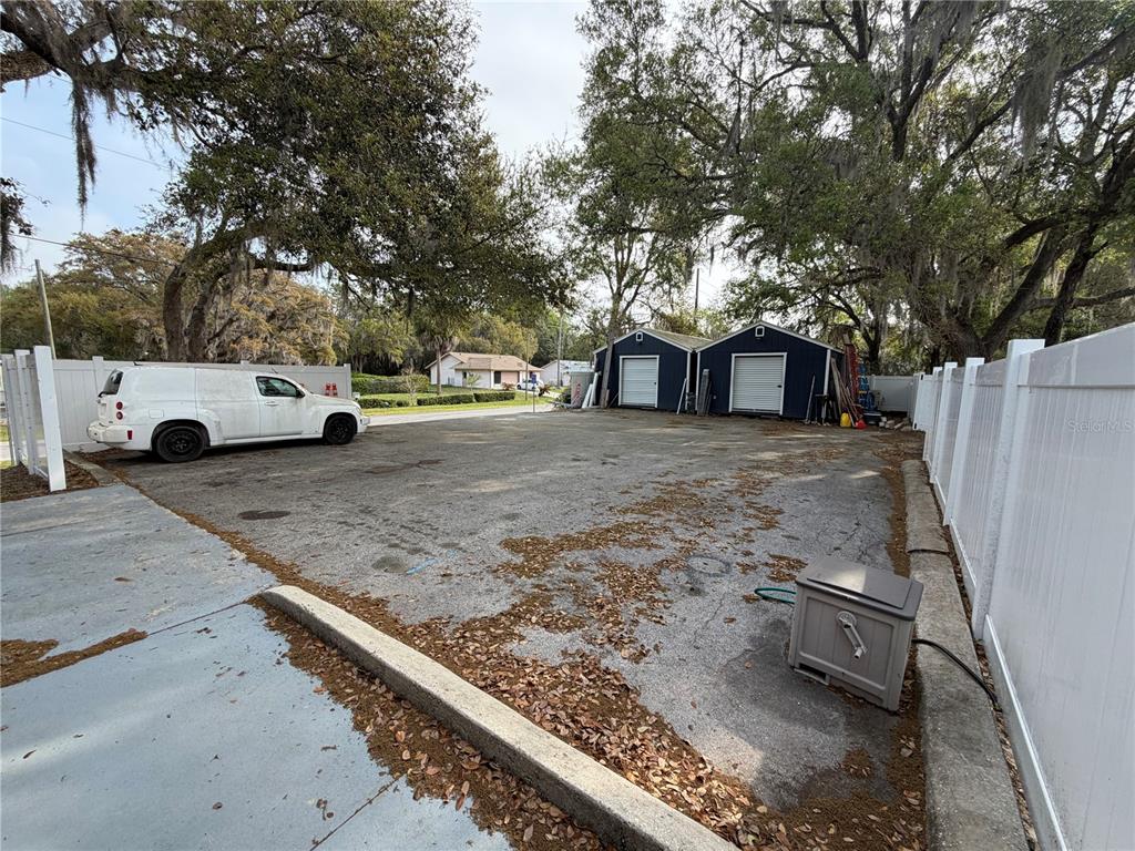 An asphalt parking area features a white van, two storage sheds, and white vinyl fencing — 9478 W MARQUETTE LANE, CRYSTAL RIVER, FL