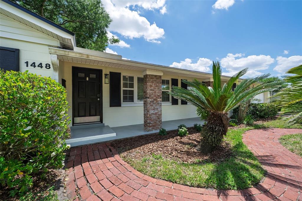 A brick walkway leads to the front entrance of a house with light-colored siding — 1448 CUMBIE STREET, ORLANDO, FL