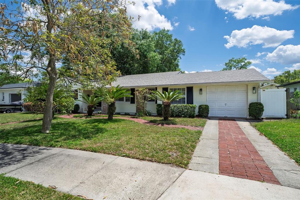 A single-story house with a brick driveway, palm trees, and a white garage door — 1448 CUMBIE STREET, ORLANDO, FL