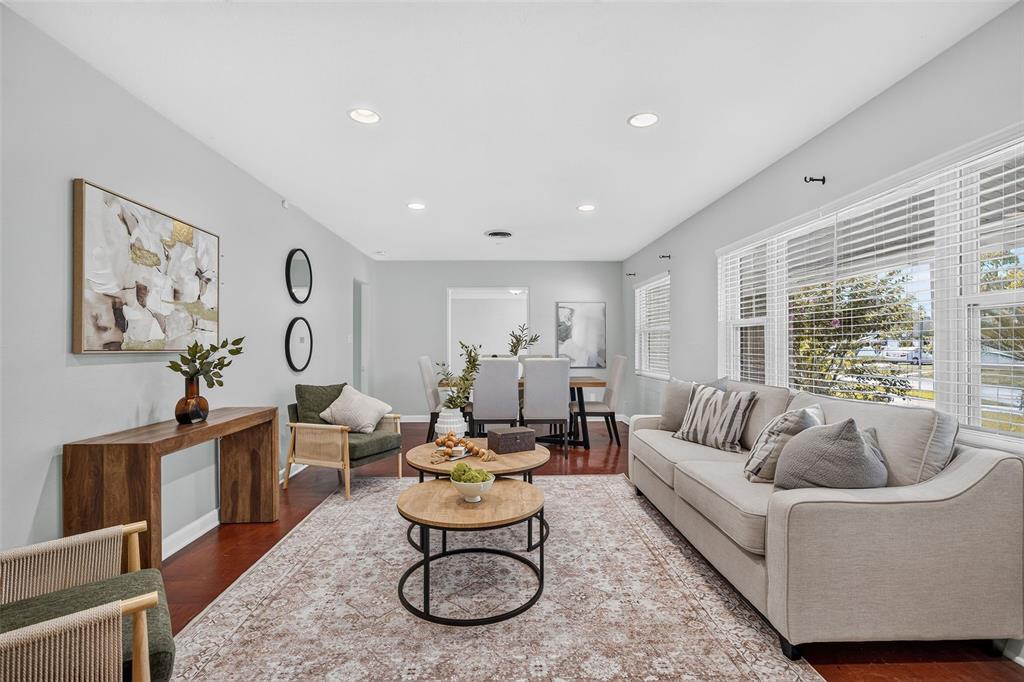 A living room with hardwood floors, a beige sofa, two coffee tables, and a dining area — 1448 CUMBIE STREET, ORLANDO, FL