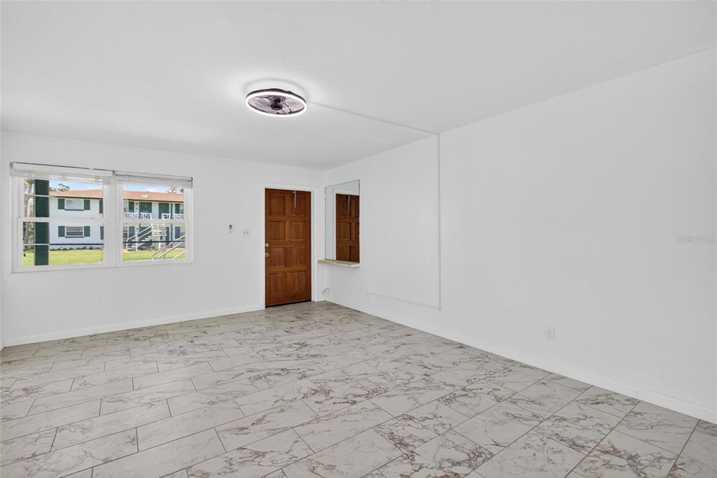 An empty room with white walls, tile flooring, a ceiling fan, and a wooden door — 1800 S PALMETTO AVENUE UNIT 1010, SOUTH DAYTONA, FL