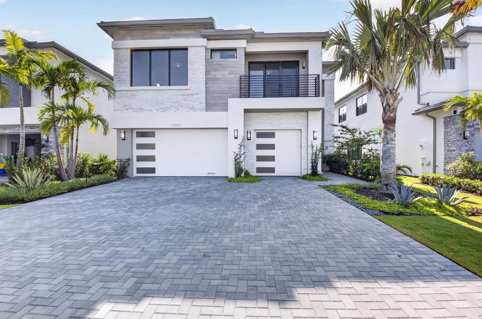 A modern two-story house features a paved driveway, a three-car garage, and a balcony — 21054 Violet Fields Way, Boca Raton FL 33434, BOCA RATON, FL