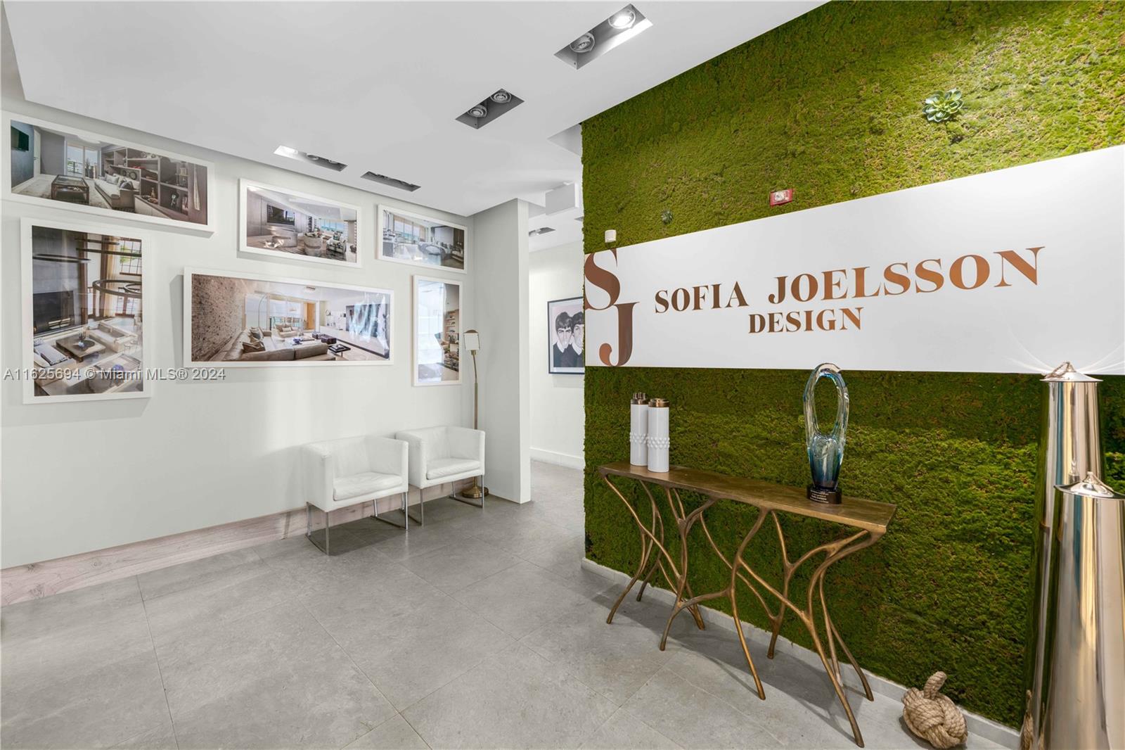 A modern office lobby features a moss wall with signage, tiled floors, and framed interior photos — 1451 Ocean Dr # 204, Miami Beach FL 33139, MIAMI BEACH, FL