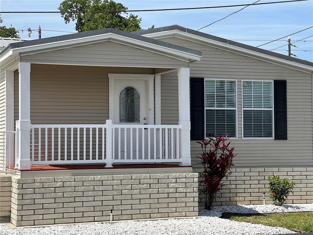 The exterior of a beige manufactured home features a front porch with white railings — 7316 AMERICANA DRIVE NE UNIT 146, ST PETERSBURG, FL