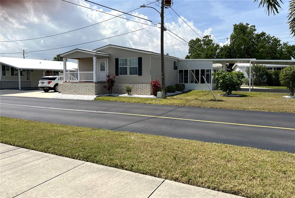 A single-story manufactured home with a front porch, carport, and screened-in side patio — 7316 AMERICANA DRIVE NE UNIT 146, ST PETERSBURG, FL