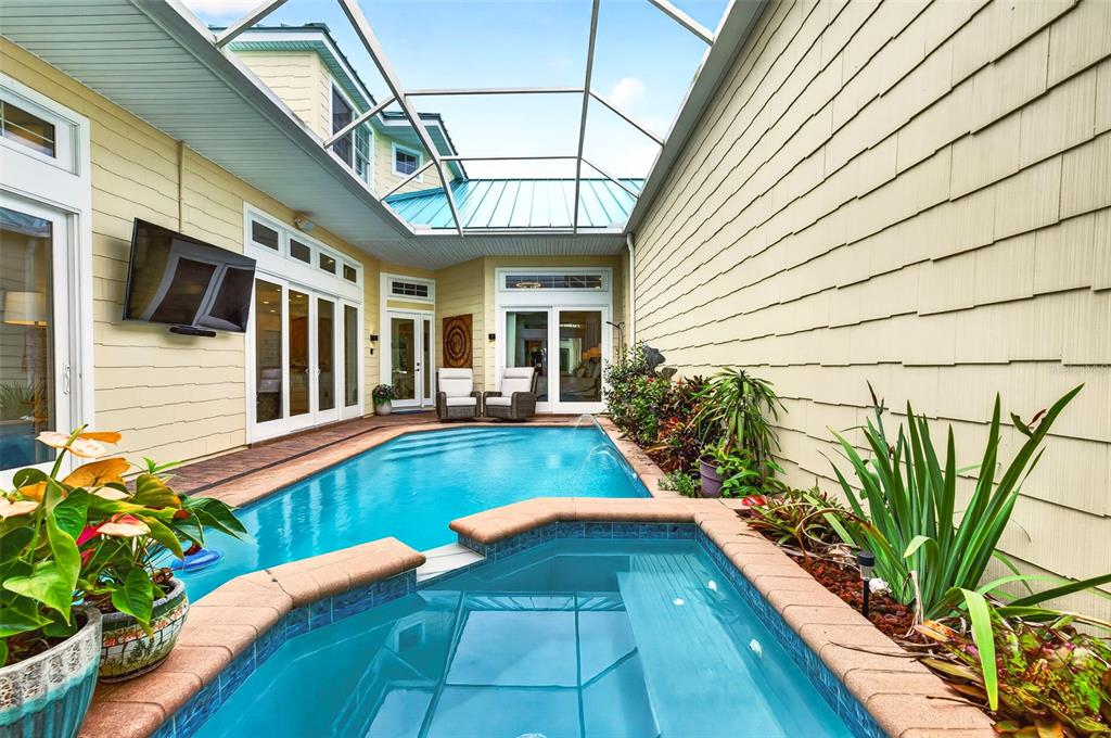 A screened-in patio features a swimming pool and hot tub next to a yellow house — 4616 OAK HAMMOCK COURT UNIT 4616, PONCE INLET, FL