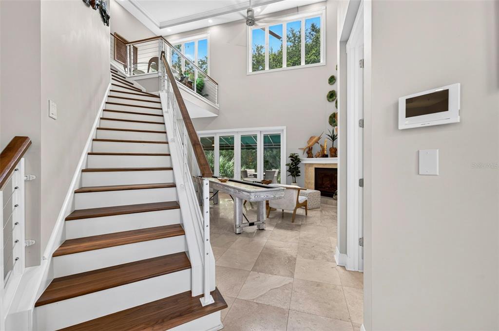 A staircase with wood treads leads to a landing overlooking a living area with tile floors — 4616 OAK HAMMOCK COURT UNIT 4616, PONCE INLET, FL
