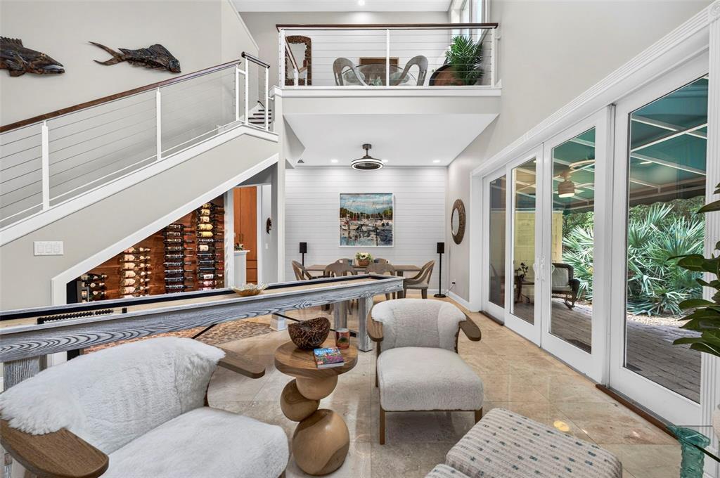A modern living area features a shuffleboard table, staircase, wine rack, and glass sliding doors — 4616 OAK HAMMOCK COURT UNIT 4616, PONCE INLET, FL