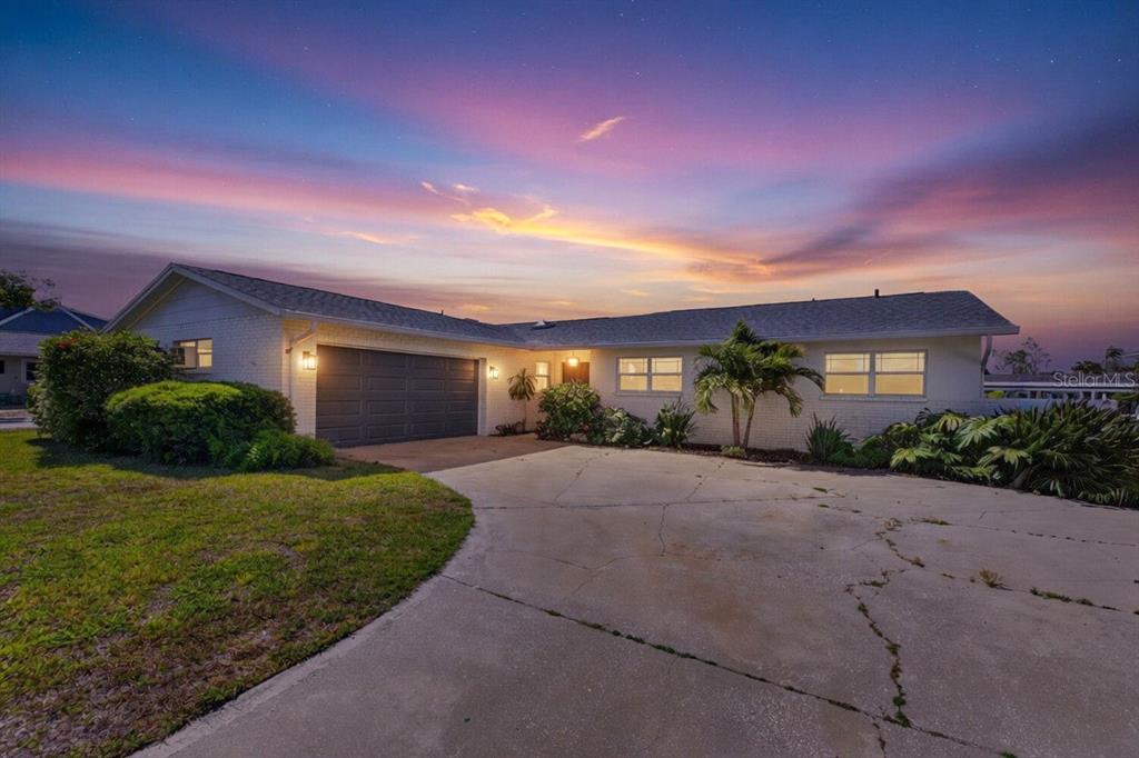A single-story white brick house with a two-car garage and a concrete driveway at sunset — 8450 FLAGSTONE DRIVE, TAMPA, FL