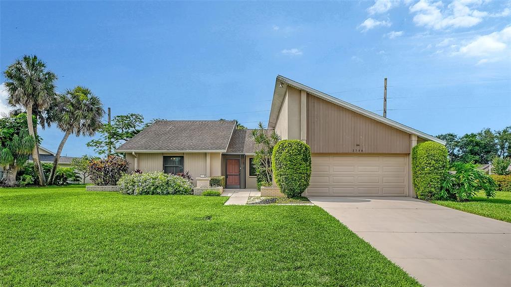 A single-story house with a tan exterior, a two-car garage, and a manicured front lawn — 3799 COUNTRYSIDE ROAD, SARASOTA, FL