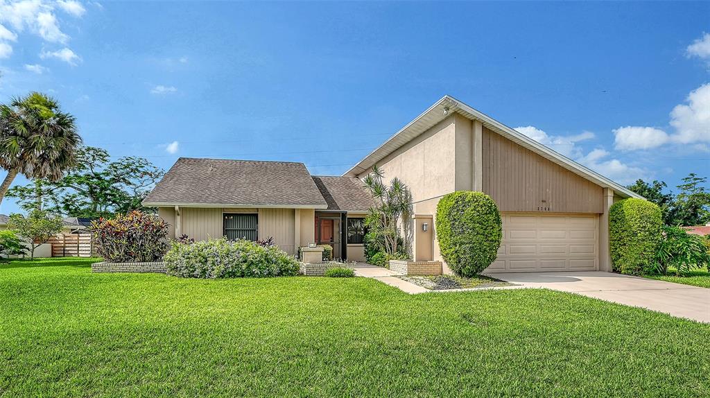 A single-story house with a beige exterior, a two-car garage, and a manicured front lawn — 3799 COUNTRYSIDE ROAD, SARASOTA, FL