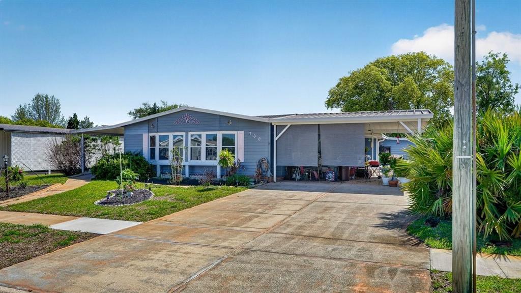 A single-story house with blue siding, a covered carport, and a concrete driveway — 780 GREENFIELD DRIVE, PORT ORANGE, FL