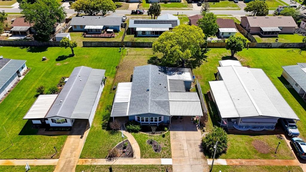 An aerial view shows three single-story houses with metal roofs and driveways in a neighborhood — 780 GREENFIELD DRIVE, PORT ORANGE, FL