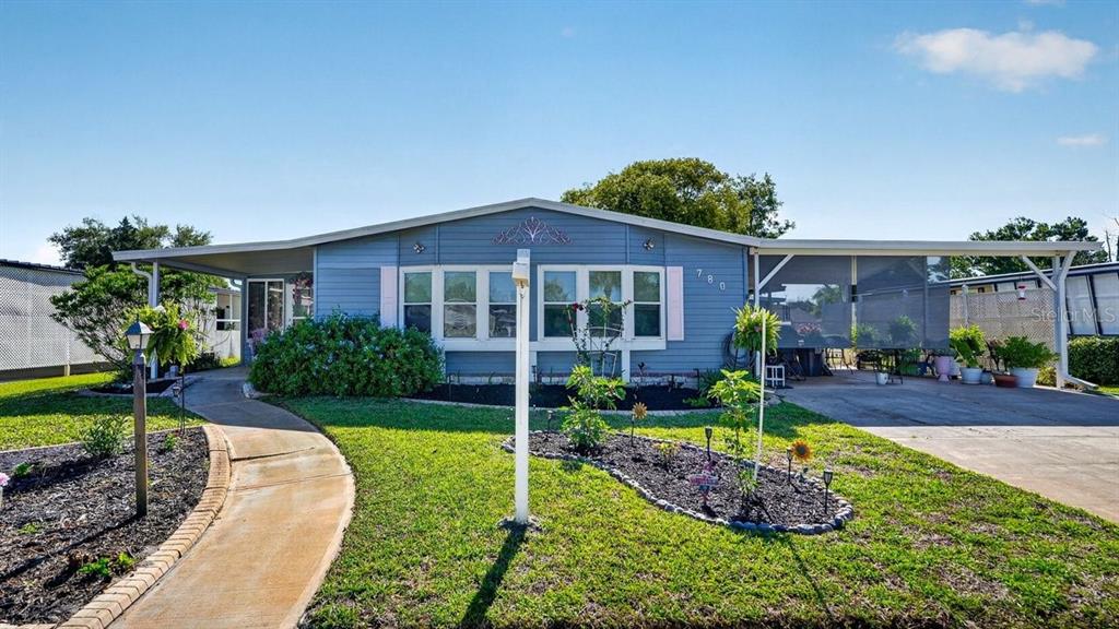 A blue single-story house features a front walkway, a carport, and a landscaped front yard — 780 GREENFIELD DRIVE, PORT ORANGE, FL
