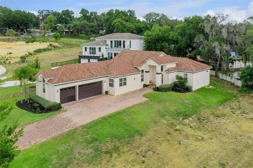 An aerial view of a single-story house with a tile roof and a brick driveway — 1837 MOORINGS COURT, CLERMONT, FL