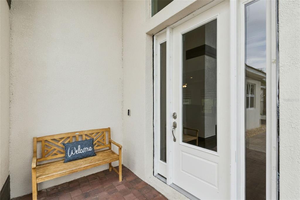 A wooden bench with a welcome pillow sits on a brick porch by a front door — 1837 MOORINGS COURT, CLERMONT, FL