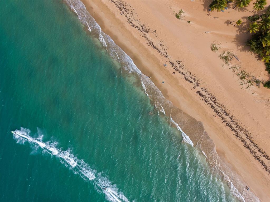 An aerial view shows a sandy beach with turquoise water and a jet ski — OCEAN FOREST Lot 2, RIO GRANDE, PR