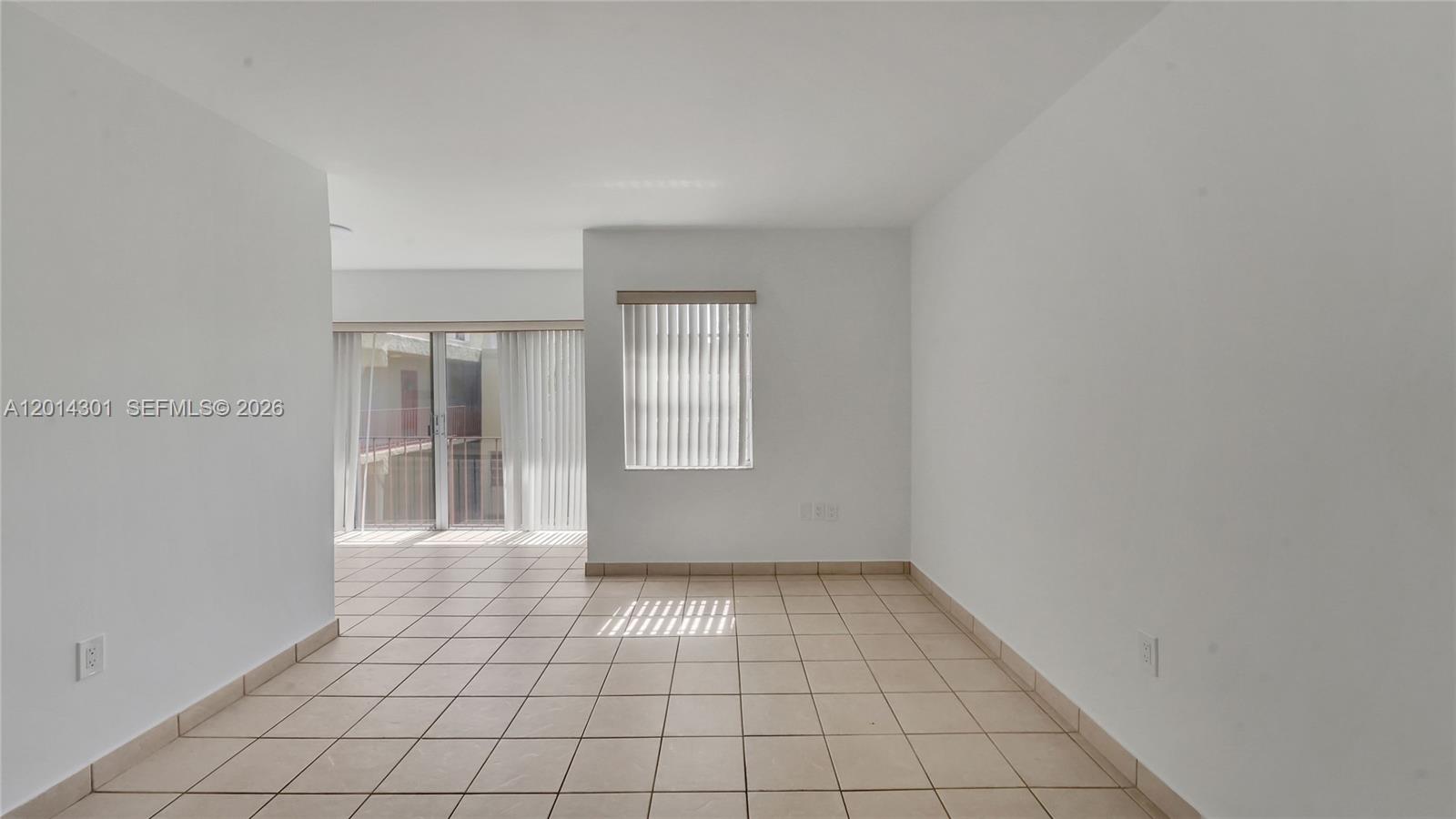 An empty room features white walls, beige tile flooring, and a sliding glass door — 9390 W Flagler St # 210A, Miami FL 33174, MIAMI, FL