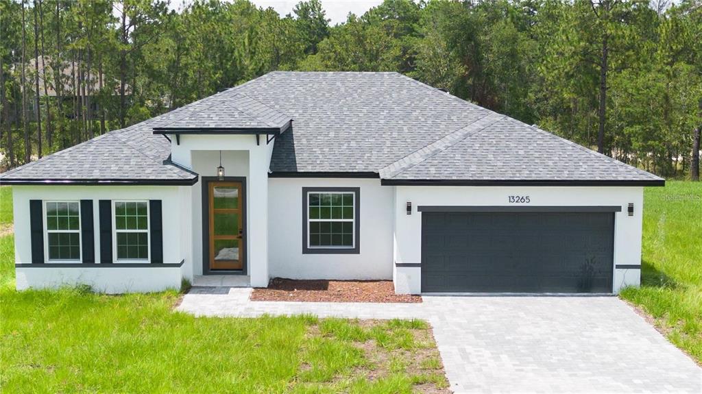 A single-story house with a white stucco exterior, dark trim, and a two-car garage — 13265 SW 85TH CIRCLE, OCALA, FL