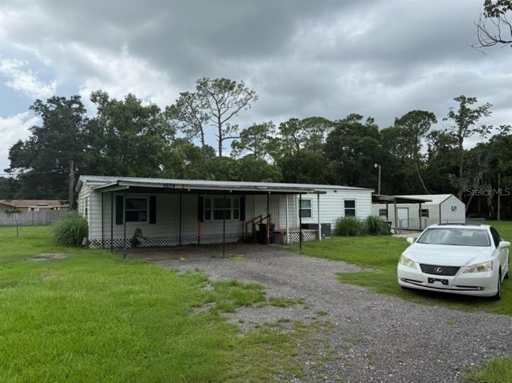 A single-story mobile home with a covered front porch and a gravel driveway — 5634 LORRAINE STREET, LAKELAND, FL