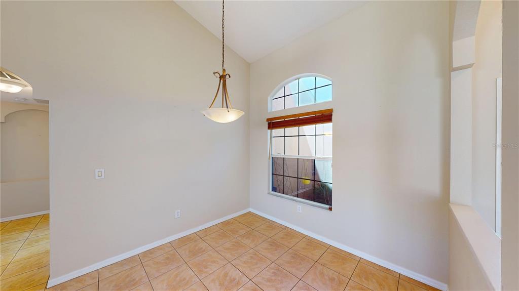 A dining area features tile flooring, a vaulted ceiling, and a large arched window — 6942 ORVICTI COURT, WESLEY CHAPEL, FL