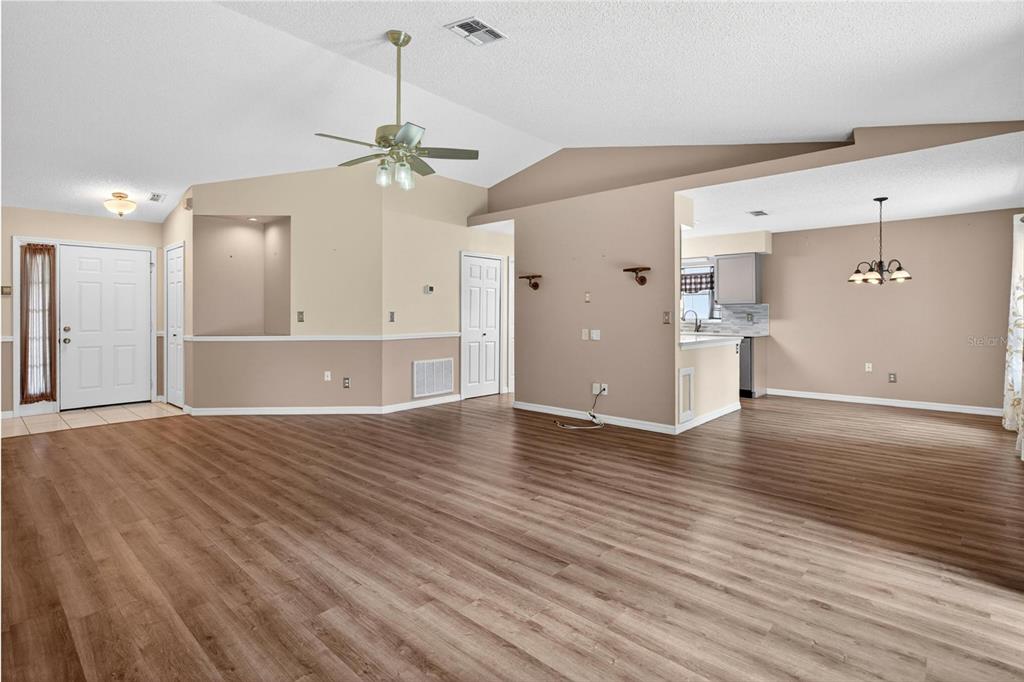 A spacious living area features light-colored walls, wood-look flooring, a vaulted ceiling, and a ceiling fan — 2127 KING RICHARDS COURT, ORANGE CITY, FL