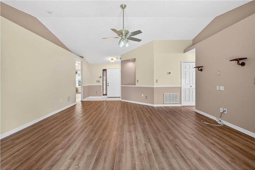 A spacious living room features vaulted ceilings, wood-look flooring, and a two-tone wall paint scheme — 2127 KING RICHARDS COURT, ORANGE CITY, FL