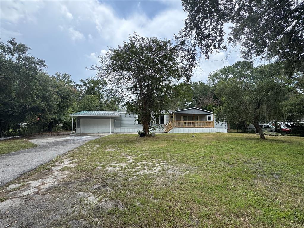A single-story manufactured home with a front porch and an attached garage sits on a lawn — 4804 KIPP CIRCLE, PLANT CITY, FL