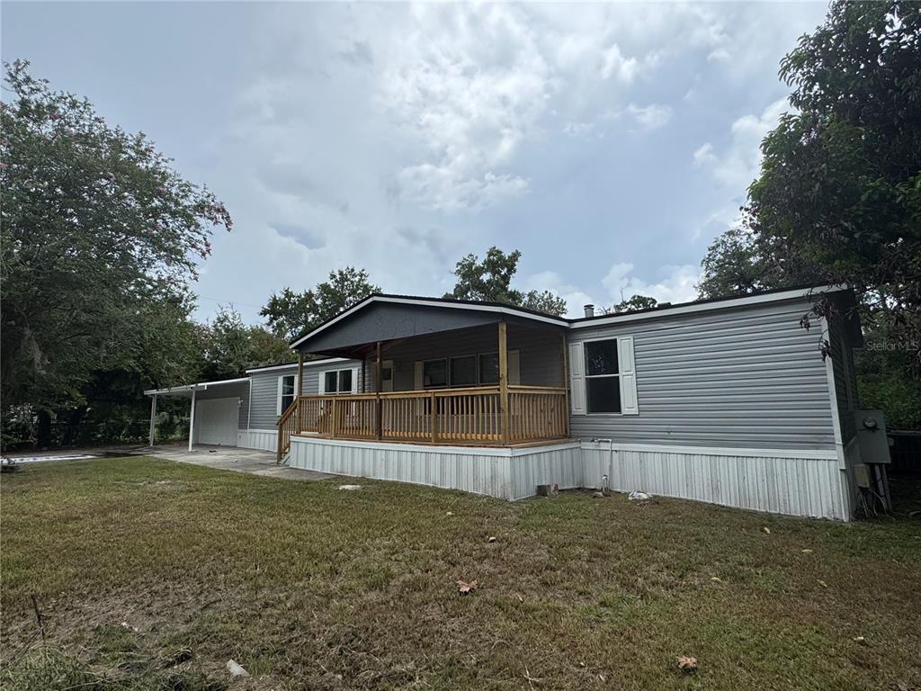 A gray manufactured home features a wooden front porch and an attached carport — 4804 KIPP CIRCLE, PLANT CITY, FL