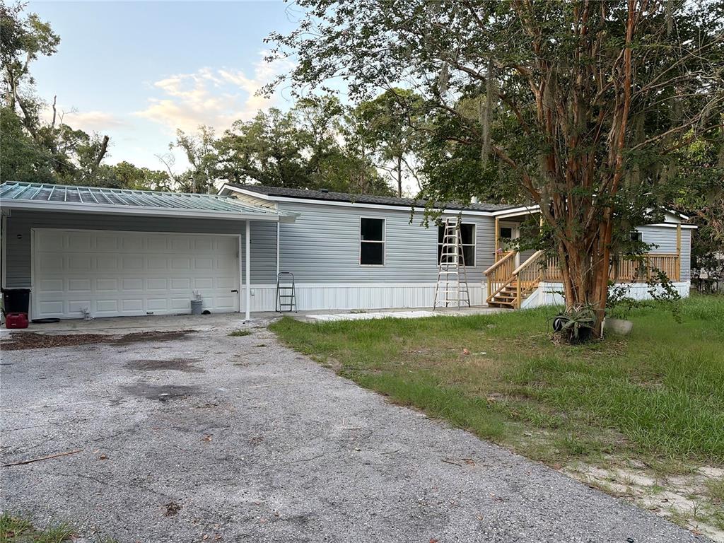 A single-story manufactured home with light gray siding, a metal-roofed carport, and a wooden porch — 4804 KIPP CIRCLE, PLANT CITY, FL