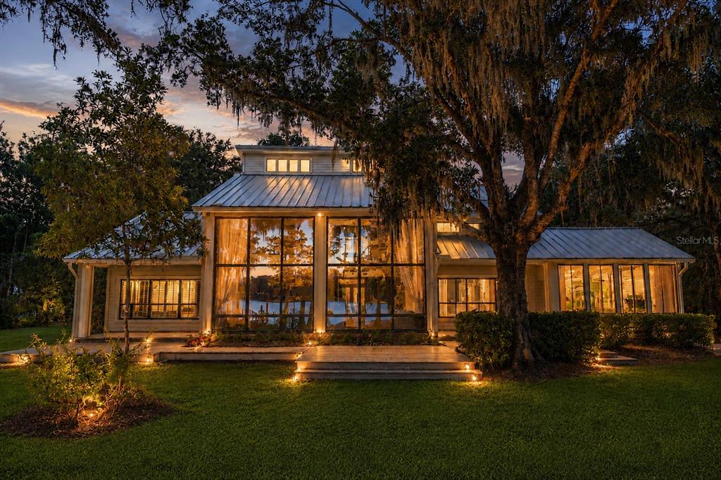 A two-story house with large glass windows and a metal roof at twilight — 17810 CRAWLEY ROAD, ODESSA, FL