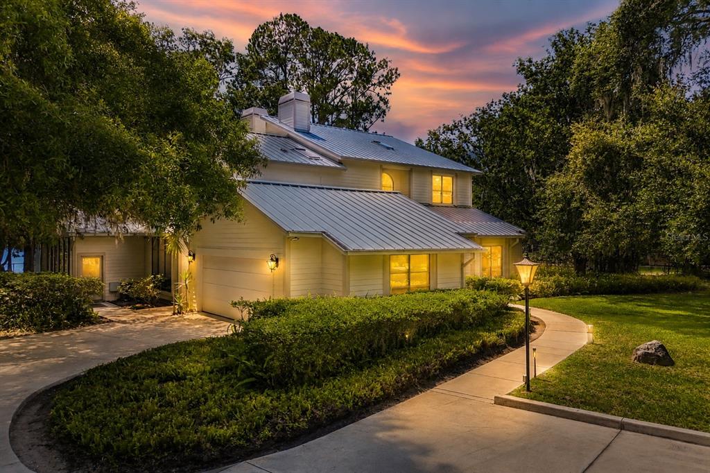 A two-story house with a metal roof and a curved walkway at dusk — 17810 CRAWLEY ROAD, ODESSA, FL