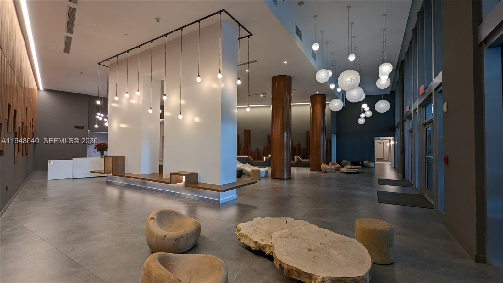 The modern lobby features a white central pillar, wood accents, and hanging globe pendant lights — 350 S Miami Ave # 702, Miami FL 33130, MIAMI, FL