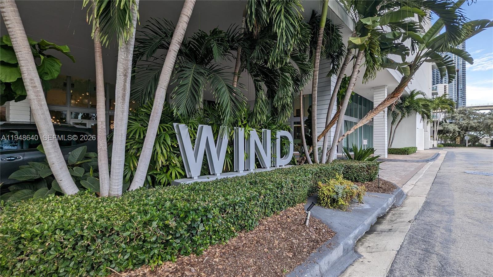 The exterior of a building features a large sign reading WIND surrounded by palm trees — 350 S Miami Ave # 702, Miami FL 33130, MIAMI, FL