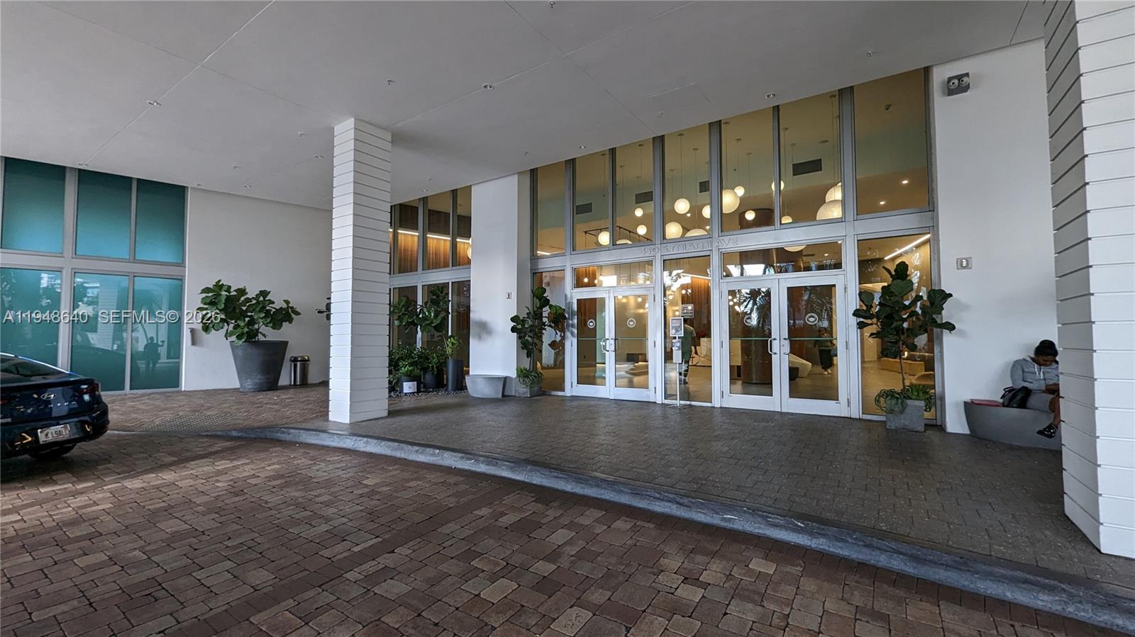 The exterior entrance features a paved driveway, glass double doors, and white structural columns — 350 S Miami Ave # 702, Miami FL 33130, MIAMI, FL