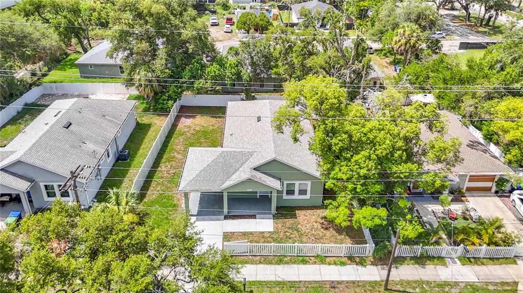 An aerial view shows a green house with a covered porch and a white fence — 509 E LAKE AVENUE, TAMPA, FL