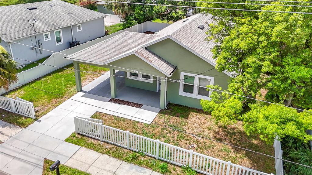 An aerial view shows a green house with a covered front porch and white fencing — 509 E LAKE AVENUE, TAMPA, FL