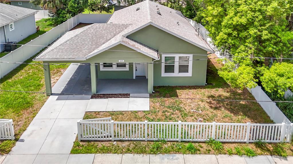 An aerial view of a green single-story house with a carport and white picket fence — 509 E LAKE AVENUE, TAMPA, FL