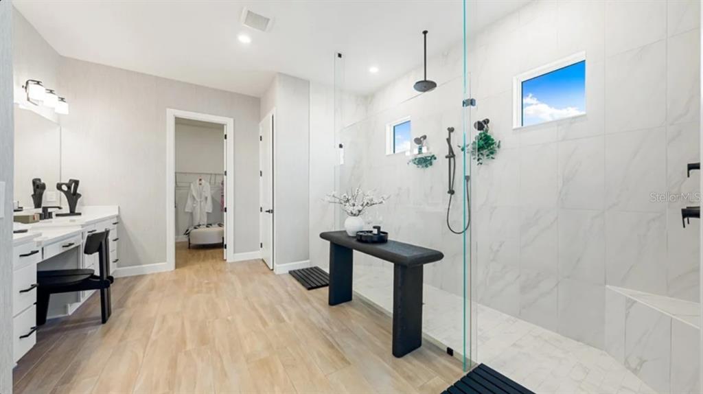 A modern bathroom features a large walk-in shower with marble tile and a black bench — 26789 VICTORIA PLACE, PUNTA GORDA, FL