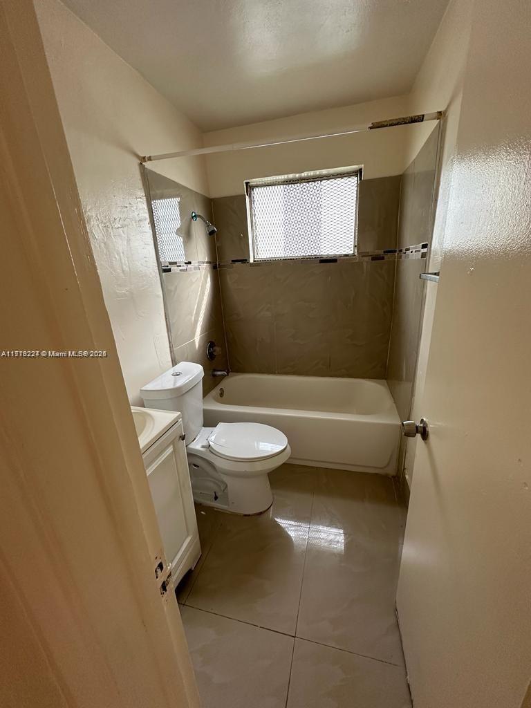 A small bathroom features a white toilet, a bathtub with a showerhead, and tiled walls — 756 NW 5th St, Hallandale Beach FL 33009, HALLANDALE BEACH, FL