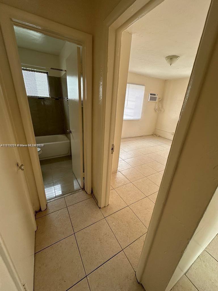 A hallway with light-colored floor tiles leads to a bathroom and an adjacent bedroom — 756 NW 5th St, Hallandale Beach FL 33009, HALLANDALE BEACH, FL